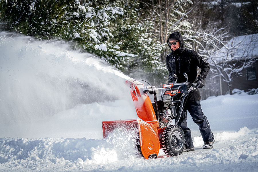 Ariens Deluxe snow blower clearing snow from a driveway